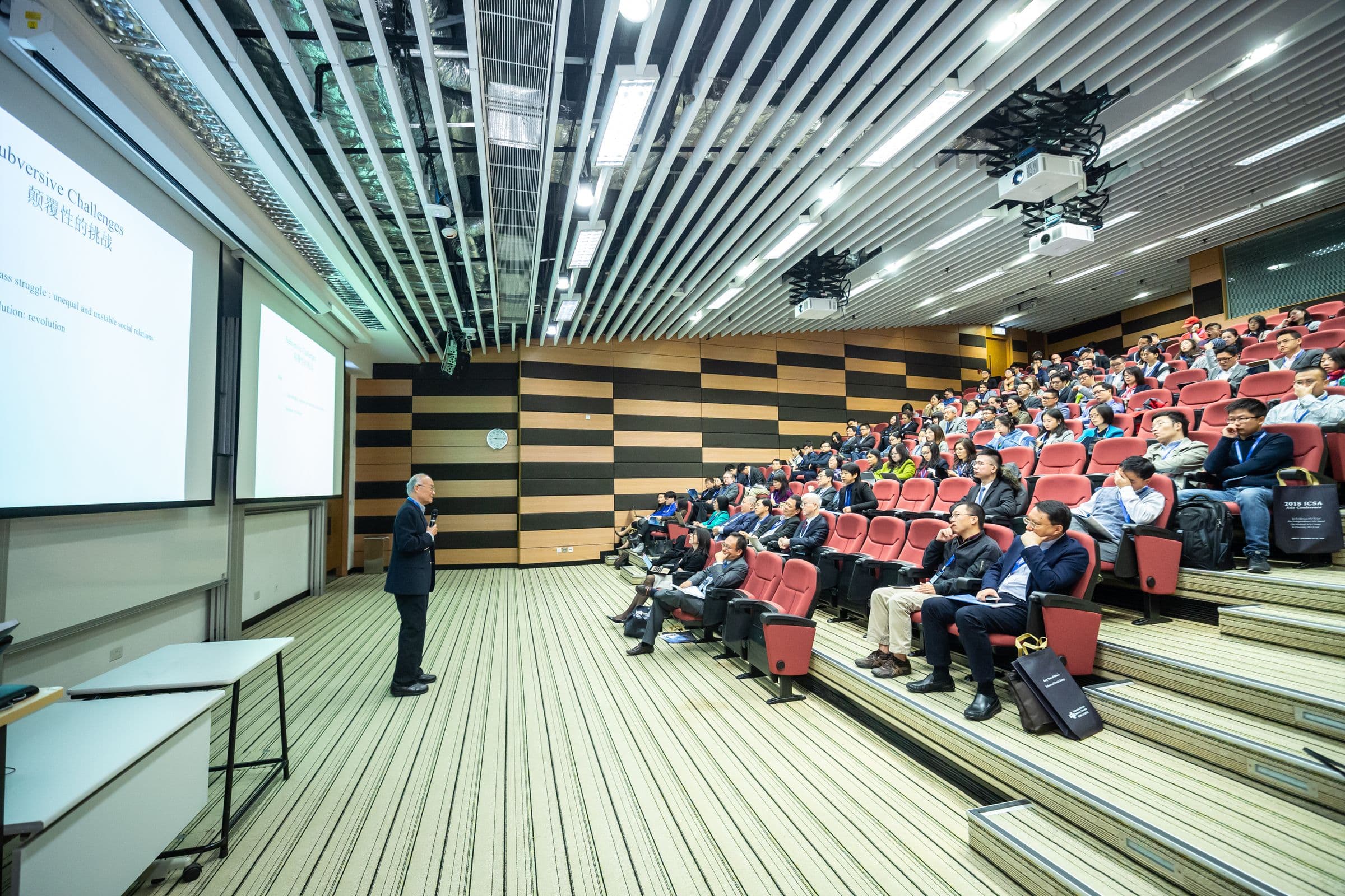 A speaker addressing a full lecture hall during a conference