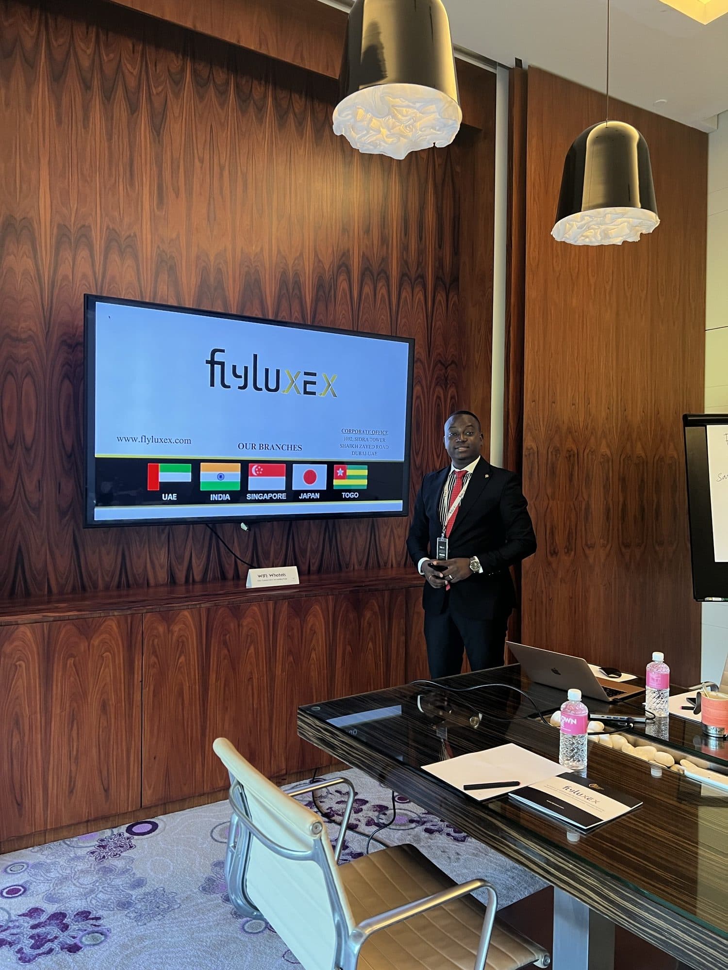 A Flyluxex representative standing beside the branch network presentation in a private boardroom