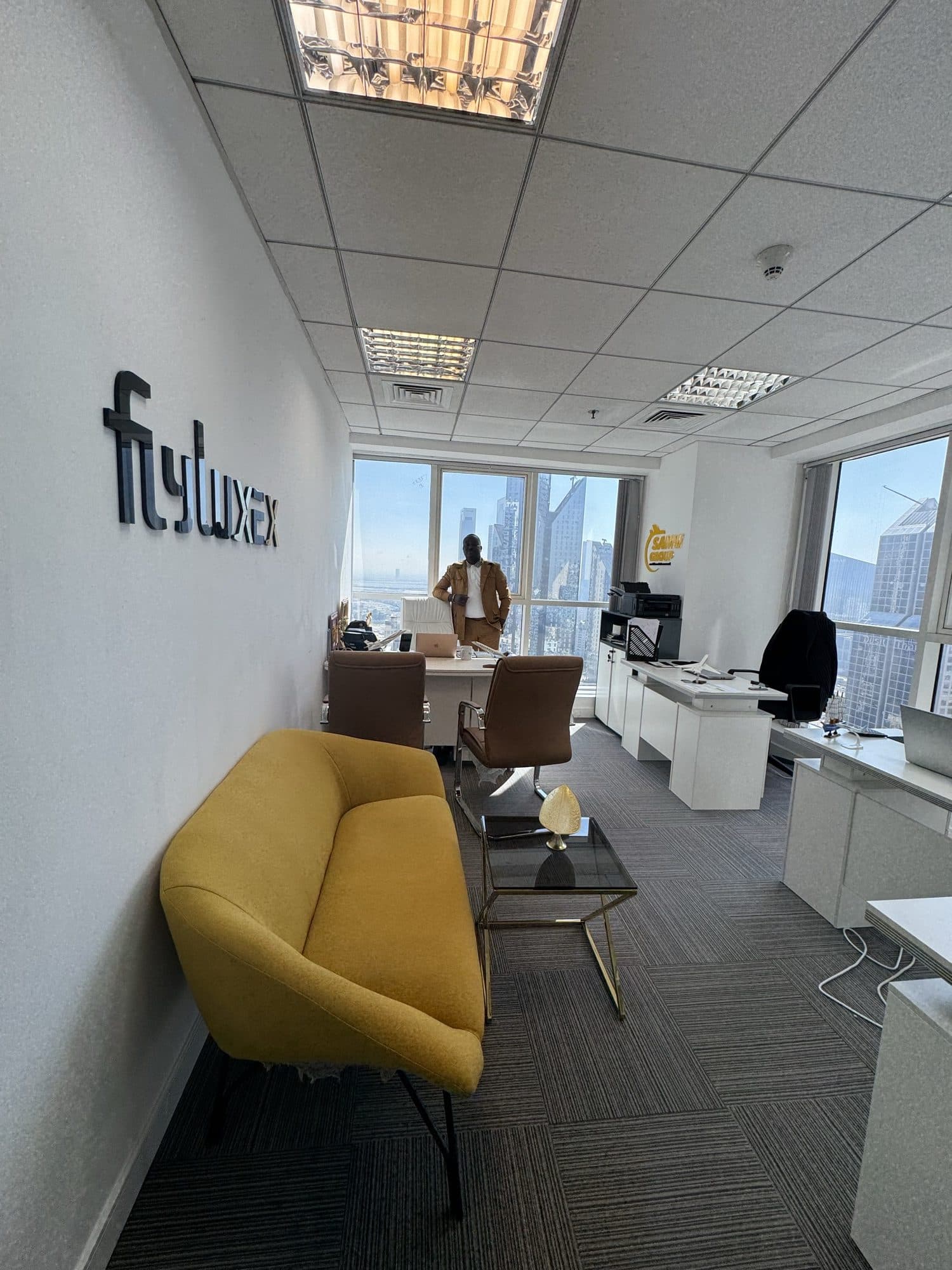The Flyluxex Dubai office, wall signage in the foreground and the skyline beyond the desk