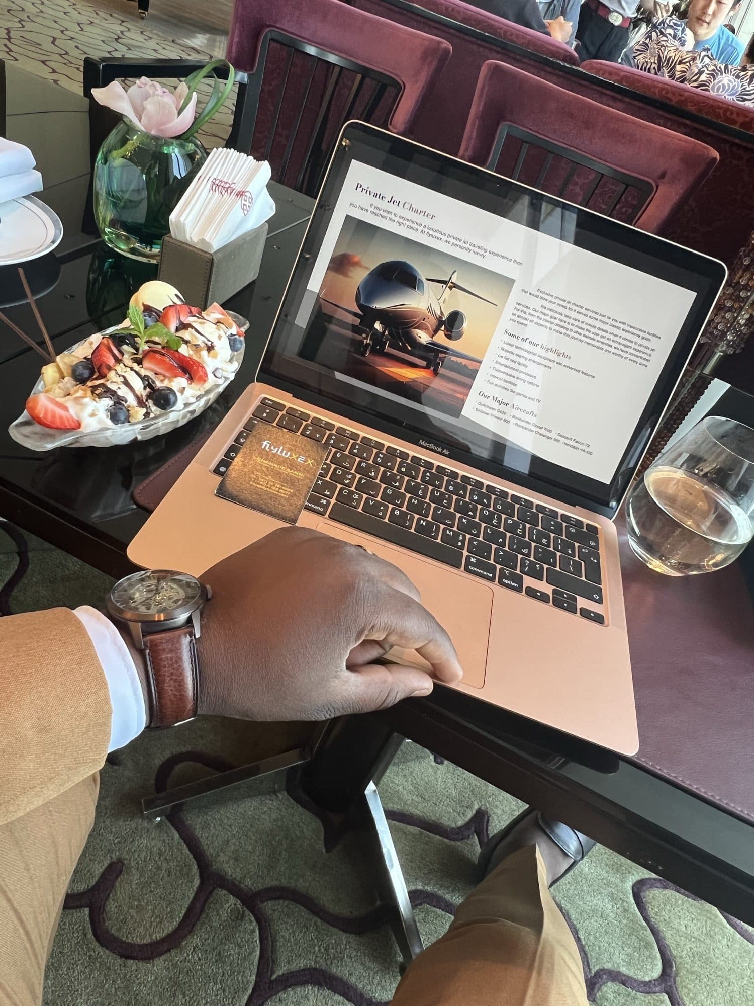 A private jet charter brochure open on a laptop at a hotel table