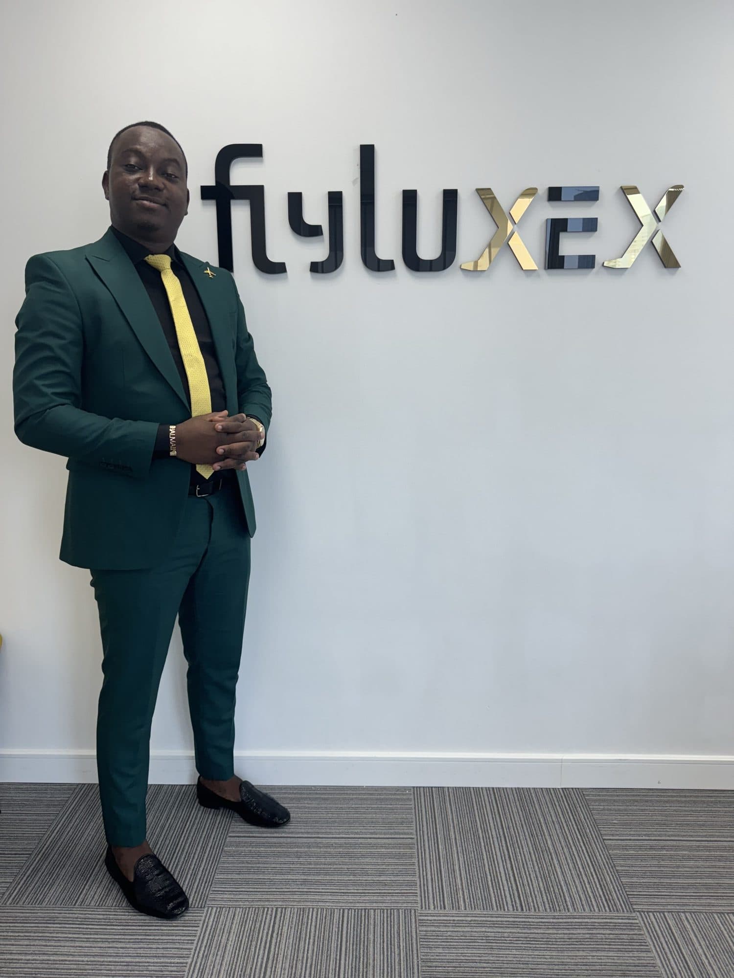 A Flyluxex representative standing beside the illuminated Flyluxex sign at the Dubai office